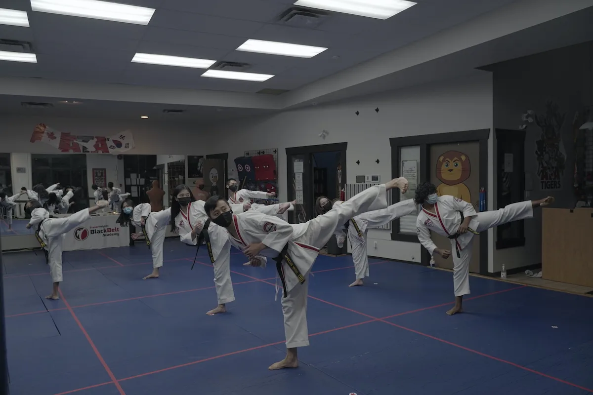 Teens and adults performing side kicks in a Taekwondo class in Surrey, BC